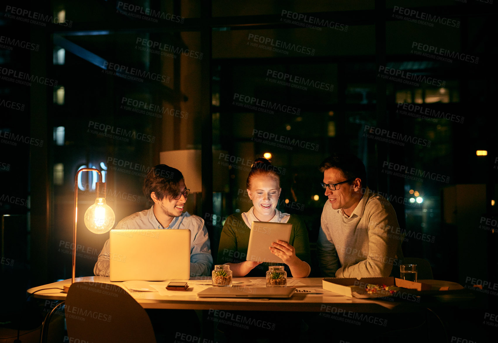 Buy stock photo Shot of businesspeople working together on a digital tablet in an office at night