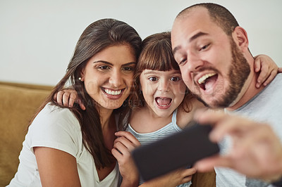 Buy stock photo Shot of a mother and father taking selfies together with their young daughter at home