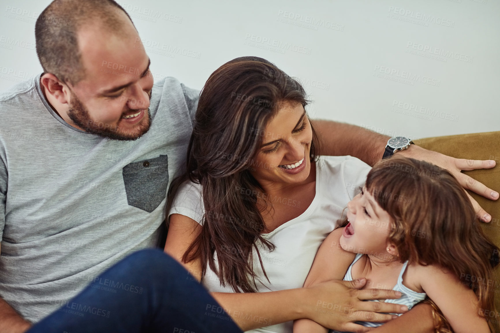 Buy stock photo Happy, love and child with parents in home for bonding, connection and family time together. Smile, sweet and girl kid hugging mother and father for care and cute moment in living room at house.