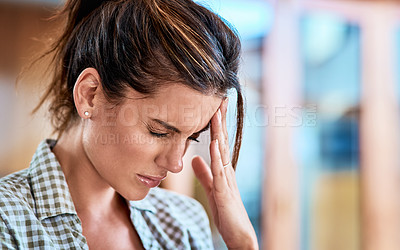 Buy stock photo Shot of a uncomfortable looking woman holding her head in discomfort due to pain at home during the day