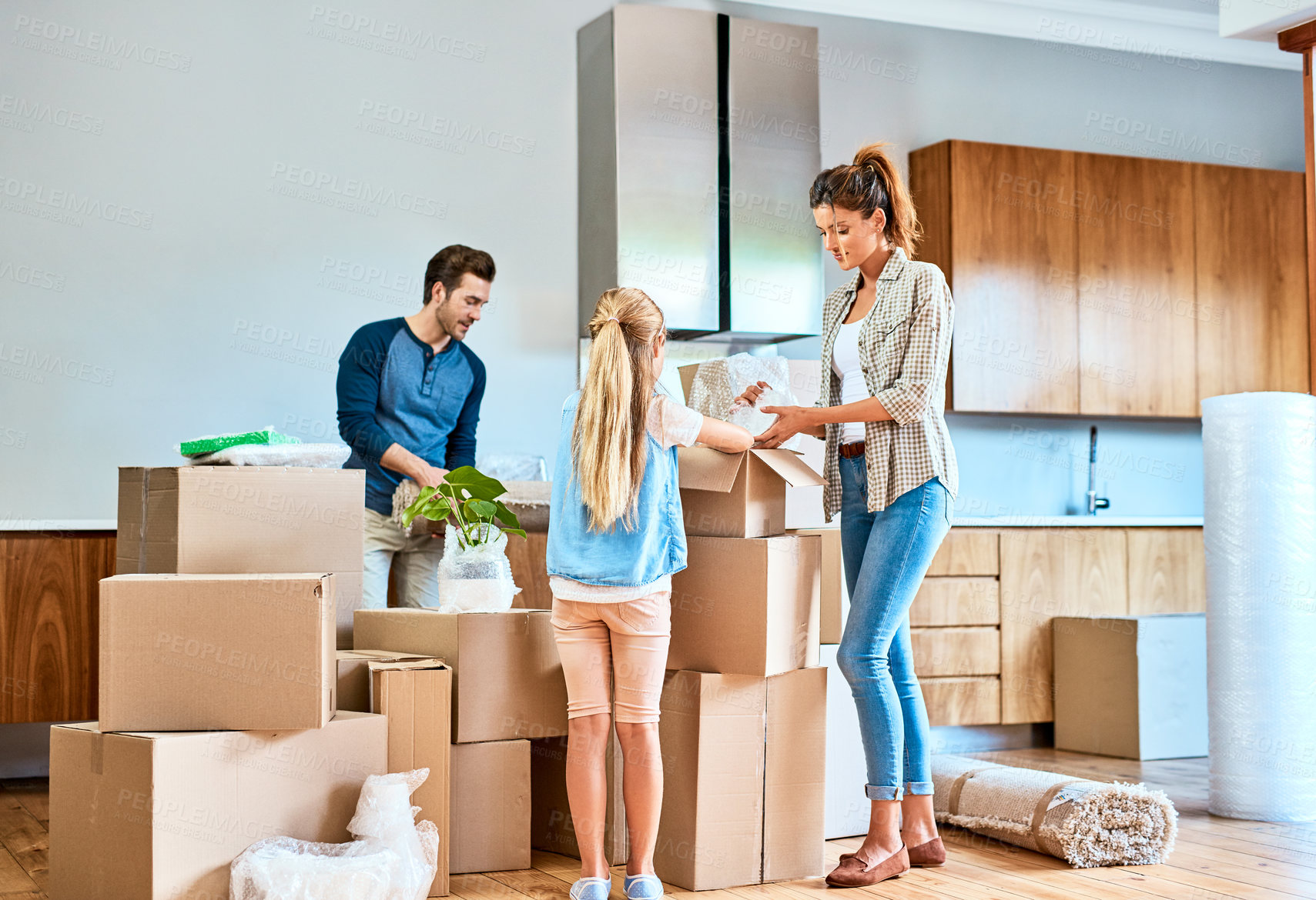 Buy stock photo Shot of a focused young family working together and unpacking boxes out in their new home inside during the day