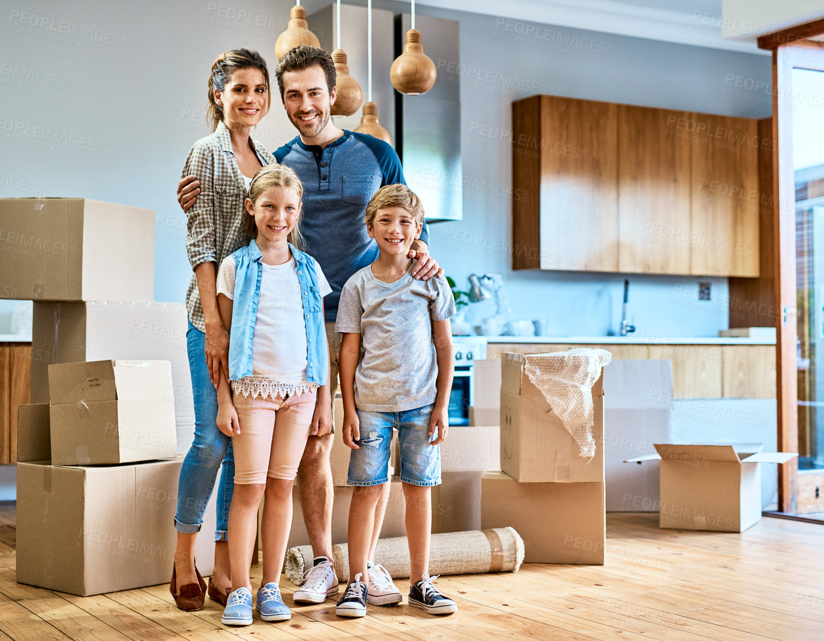 Buy stock photo Portrait of a cheerful young family standing together in their new home inside during the day