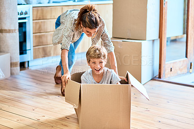 Buy stock photo Shot of a cheerful young woman pushing her son around in a box imagining its a car inside at home during the day