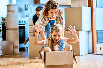 Buy stock photo Shot of a cheerful young woman pushing her daughter around in a box imagining its a car inside at home during the day
