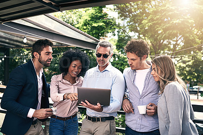 Buy stock photo Shot of a group of businesspeople working together on a laptop outside