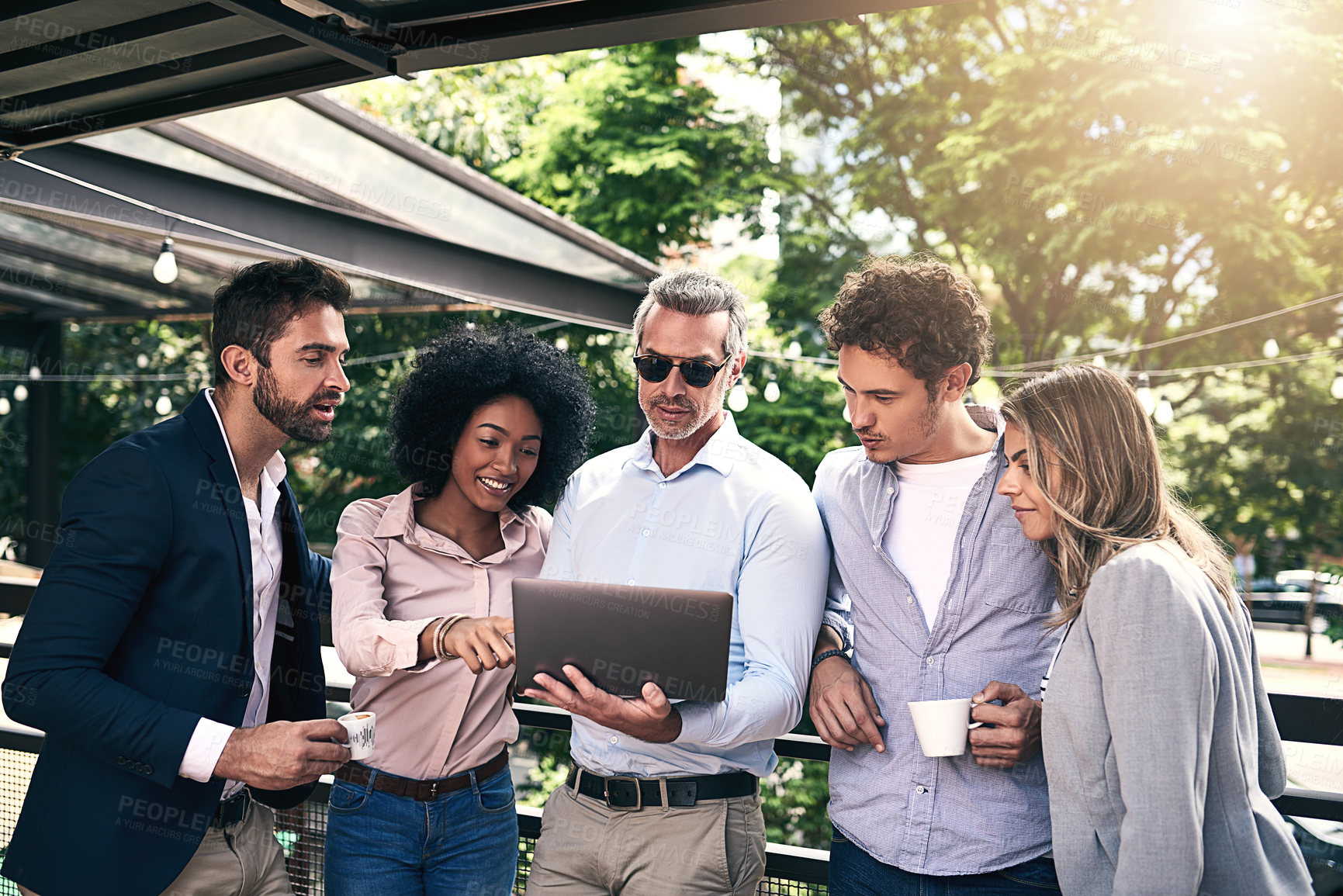 Buy stock photo Shot of a group of businesspeople working together on a laptop outside