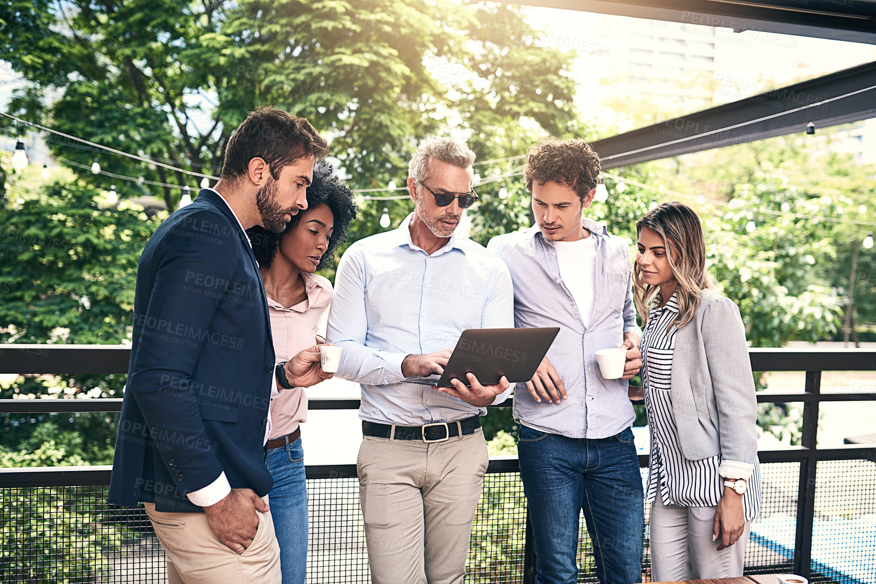 Buy stock photo Shot of a group of businesspeople working together on a laptop outside