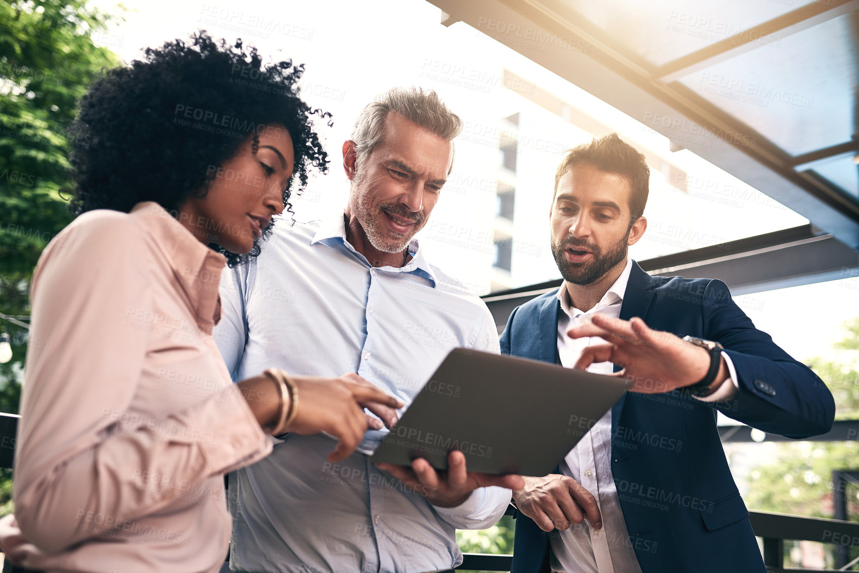 Buy stock photo Shot of a group of businesspeople working together on a laptop outside