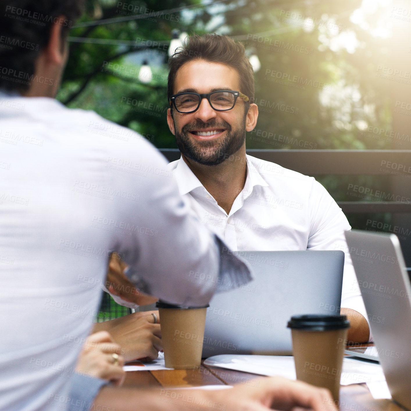 Buy stock photo Shot of businessmen shaking hands during a meeting at a cafe