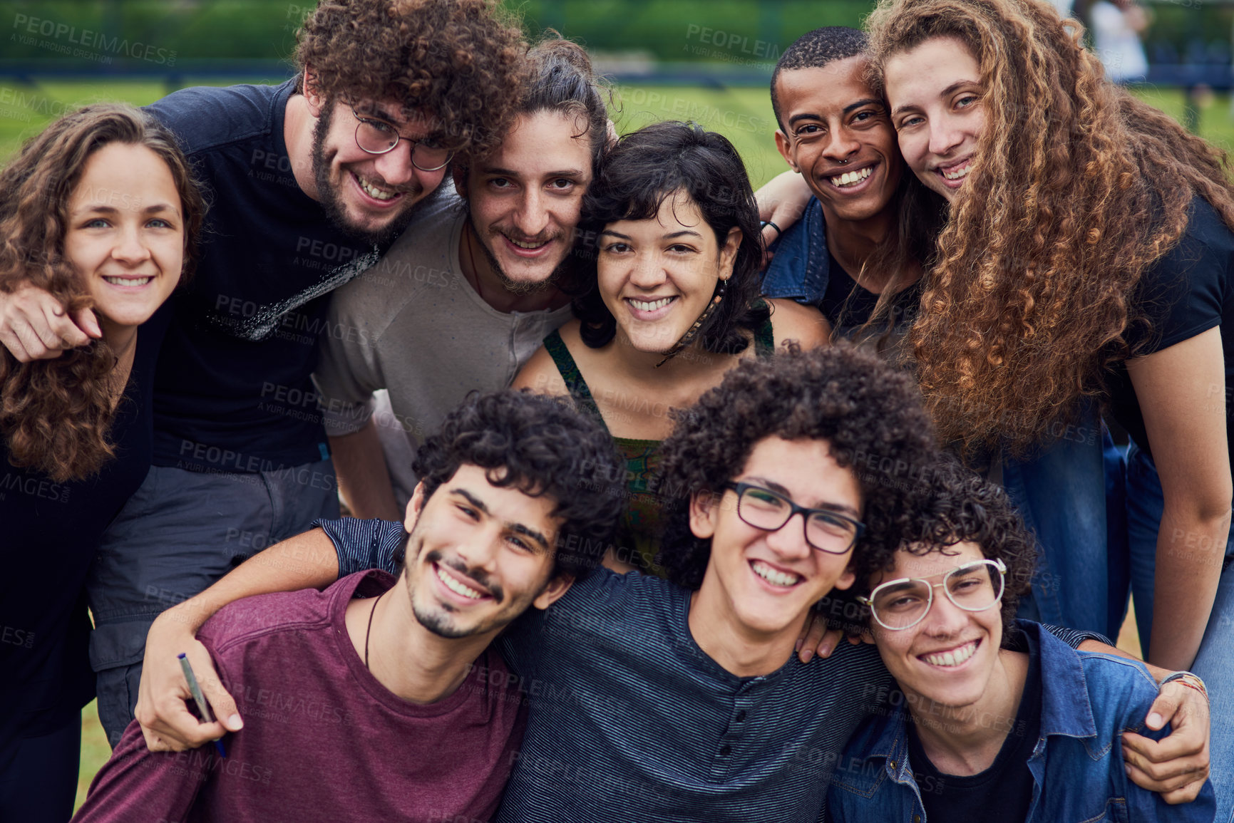 Buy stock photo Portrait of a group of young students standing arms around each other outside in a park during the day