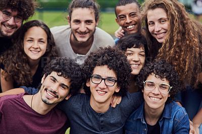 Buy stock photo Portrait of a group of young students standing arms around each other outside in a park during the day