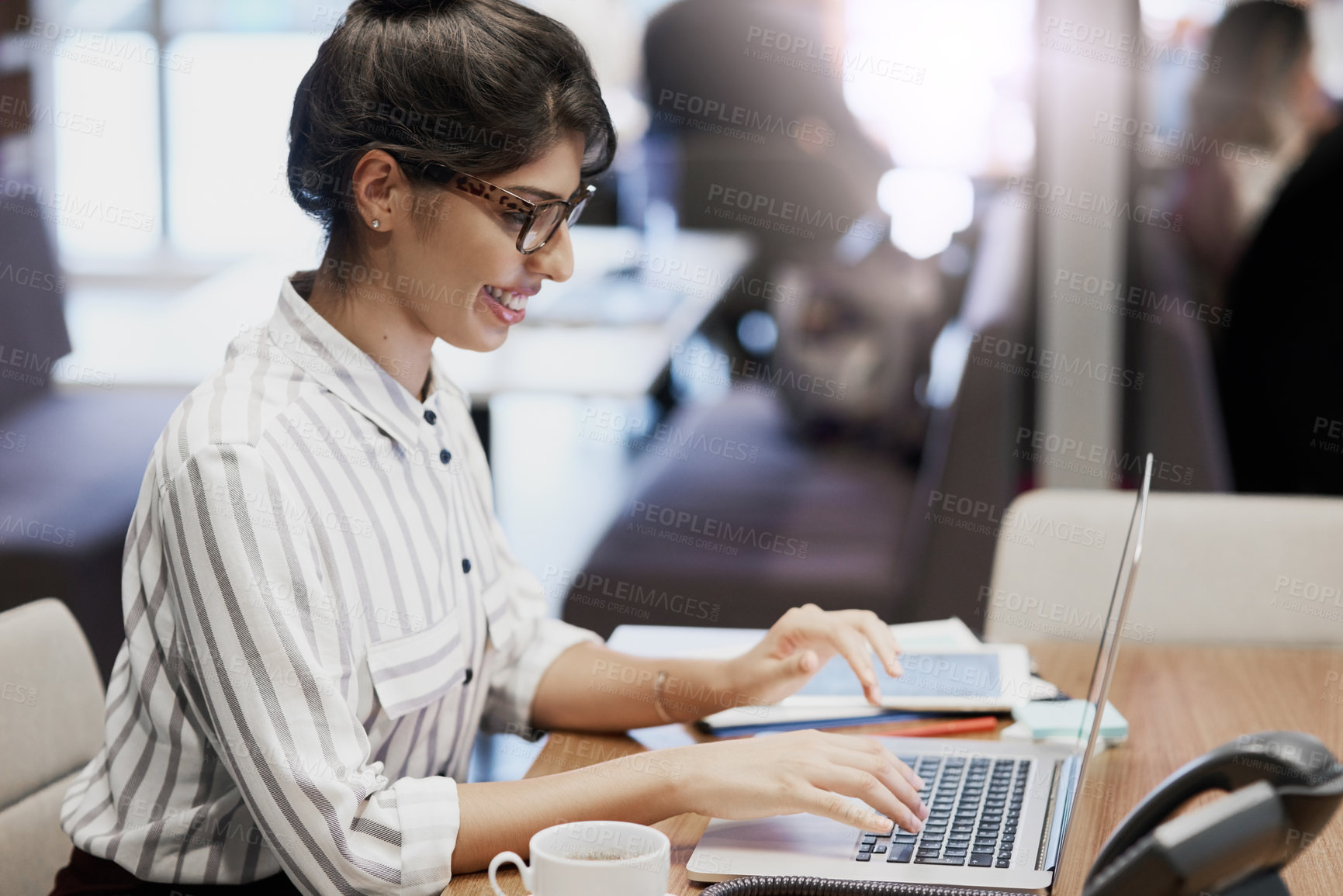 Buy stock photo Shot of a confident young businesswoman working on a laptop in an office