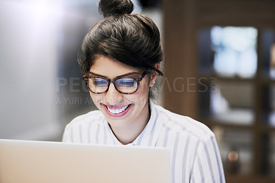 Buy stock photo Shot of a confident young businesswoman working on a laptop in an office