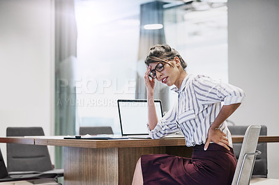 Buy stock photo Shot of a young businesswoman experiencing back pain while working in an office
