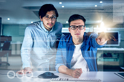Buy stock photo Portrait of two young male programmers working on a computer together in the office at night