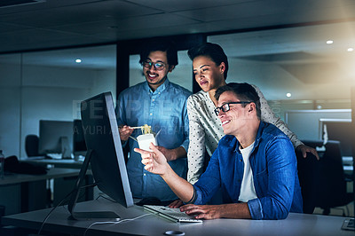 Buy stock photo Shot of a group of programmers working together on a computer in the office at work during the night