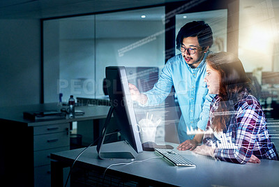 Buy stock photo Shot of two focussed young programmers working together on a computer in the office at work during the night