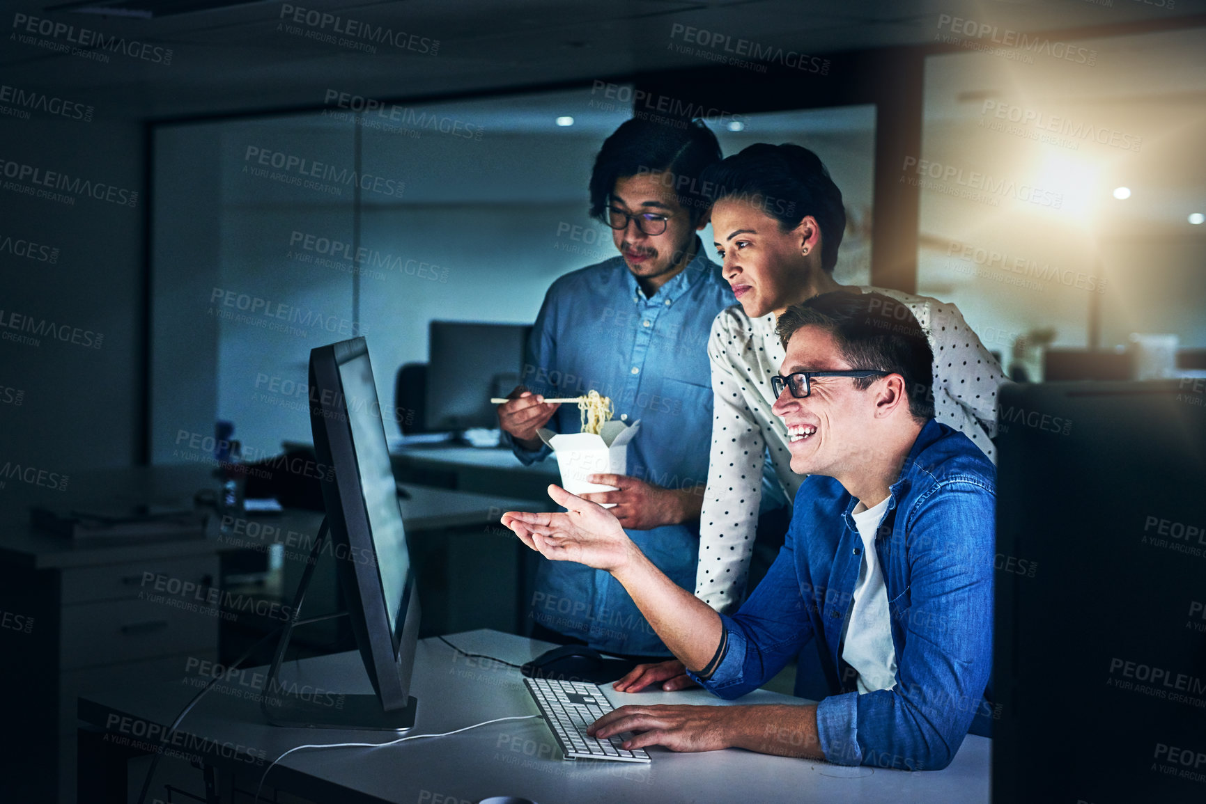 Buy stock photo Shot of a group of programmers working together on a computer in the office at work during the night