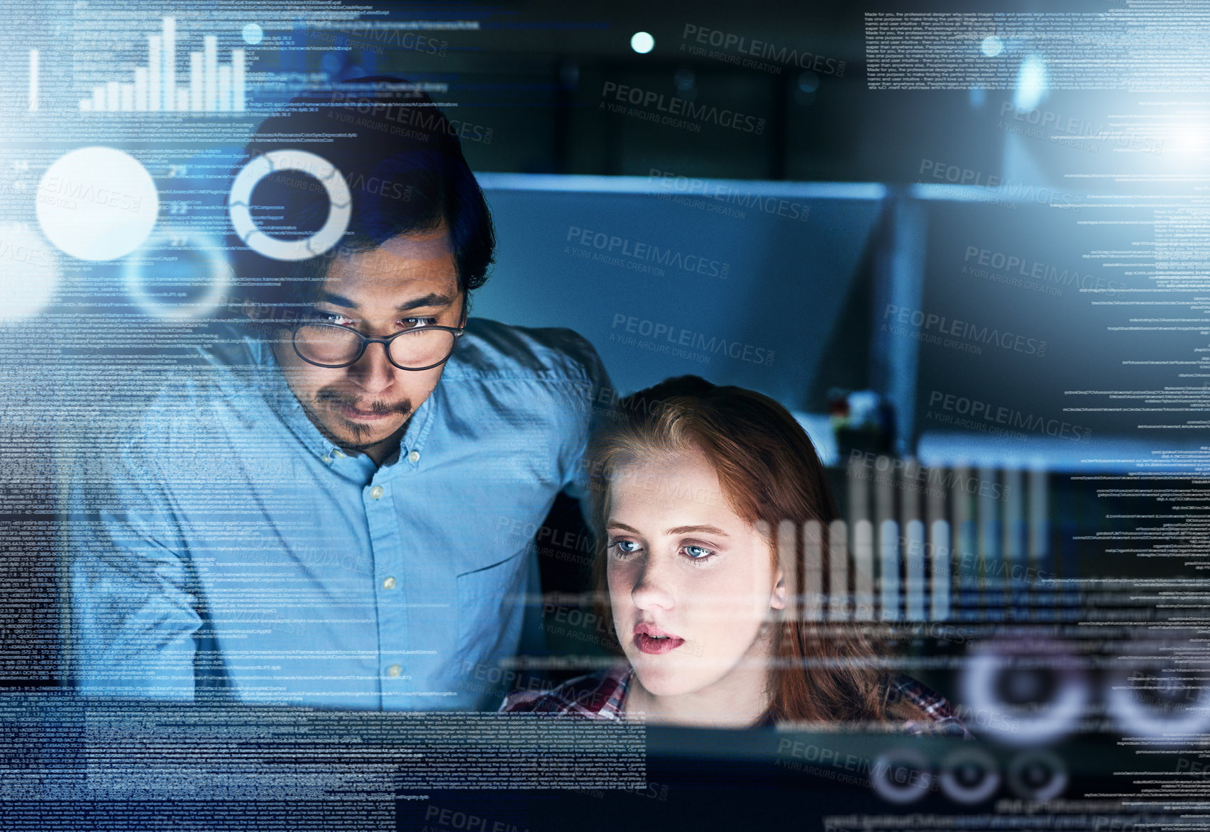 Buy stock photo Shot of two focussed young programmers working together on a computer in the office at work during the night