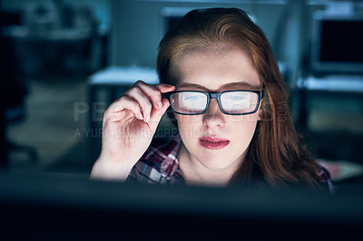 Buy stock photo Shot of a focused young female programmer working on a computer in the office at work during the night