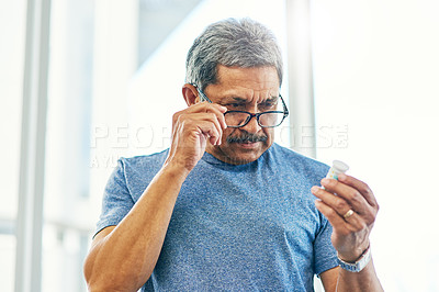 Buy stock photo Cropped shot of a handsome senior man reading a bottle of prescription medication