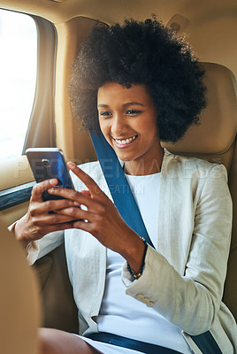 Buy stock photo Shot of a cheerful young businesswoman browsing on her cellphone while being seated in the passenger seat of a car on her way to work