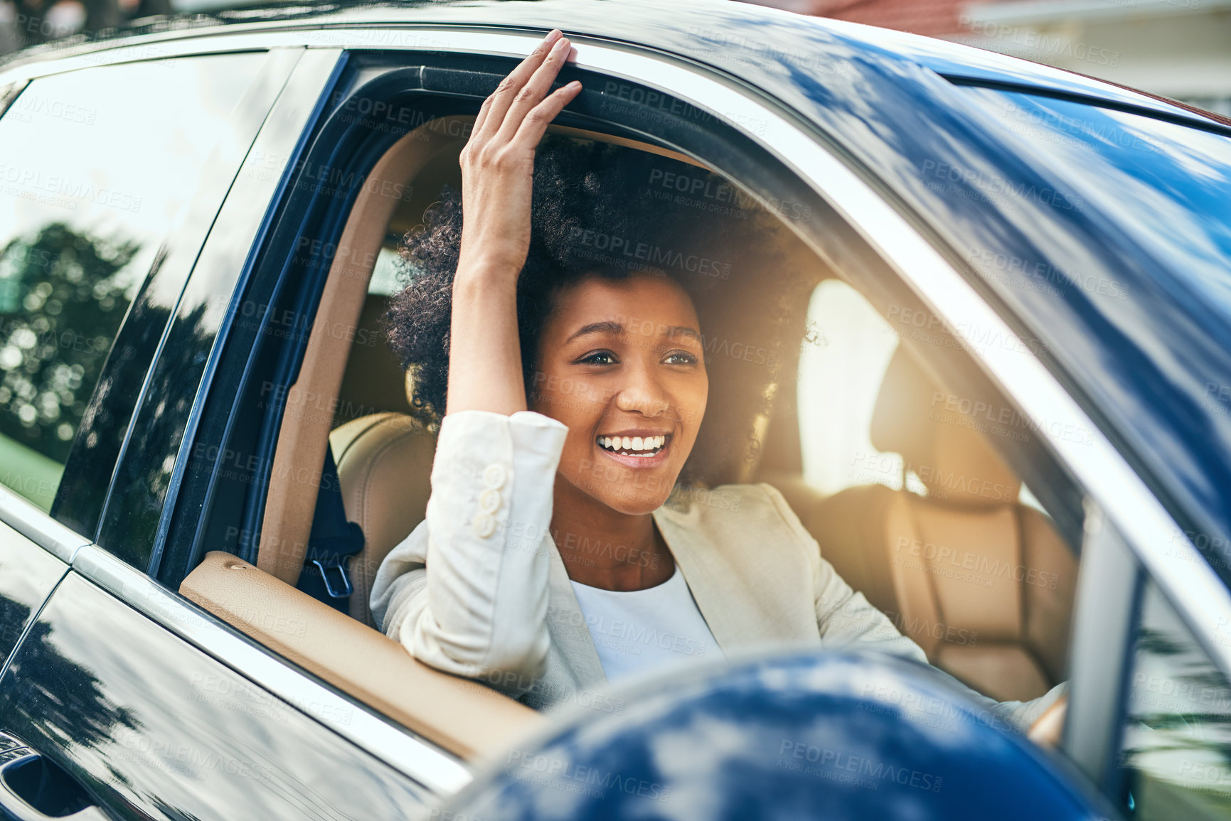 Buy stock photo Shot of a cheerful young businesswoman driving in a car to work with her arm leaning out of the vehicle during the day