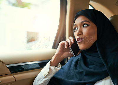 Buy stock photo Shot of a young businesswoman talking on her mobile phone while being seated in the back of a car on her way to work