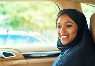Buy stock photo Shot of a cheerful young businesswoman seated in the back of a car while driving to work during the day