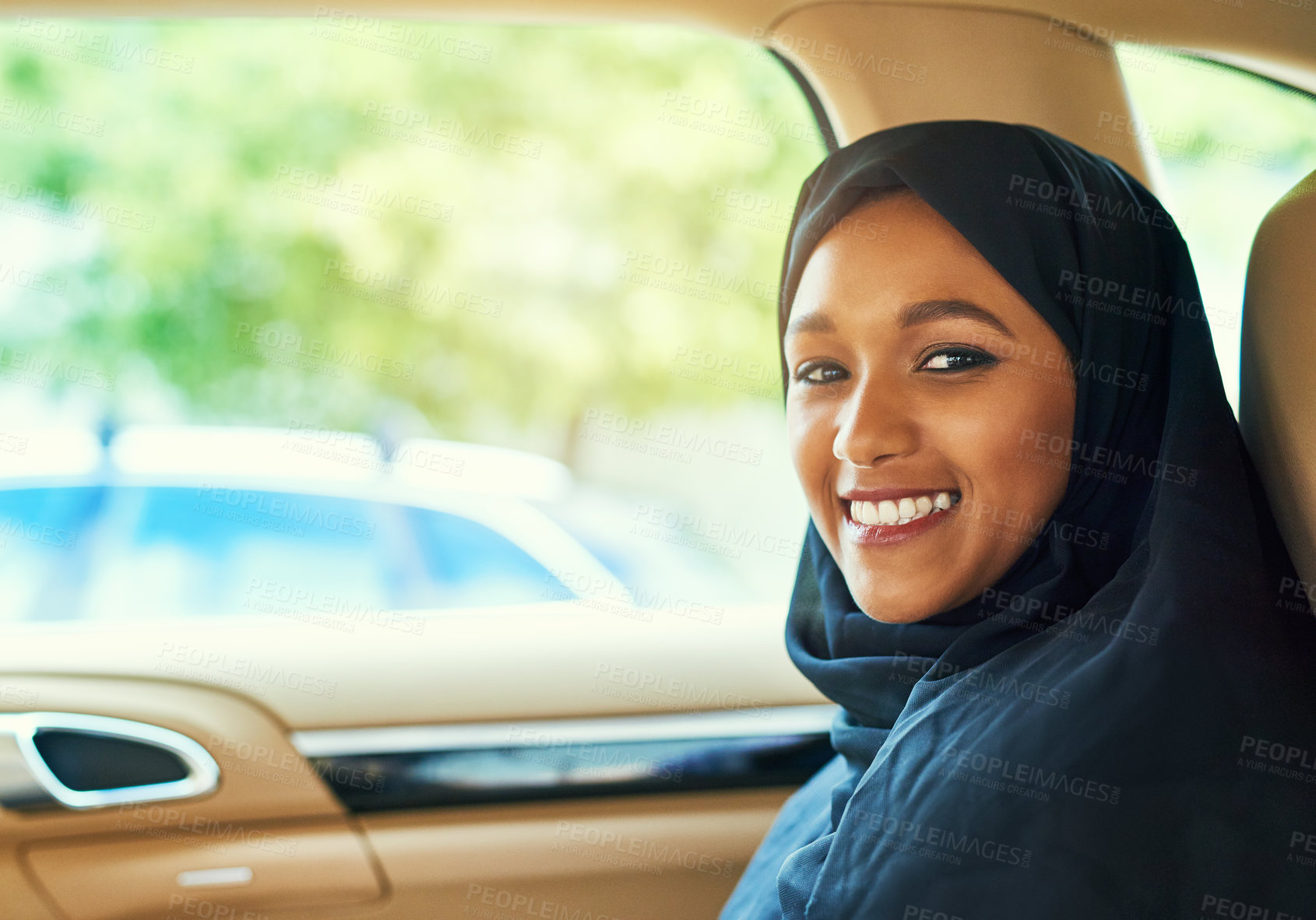 Buy stock photo Shot of a cheerful young businesswoman seated in the back of a car while driving to work during the day