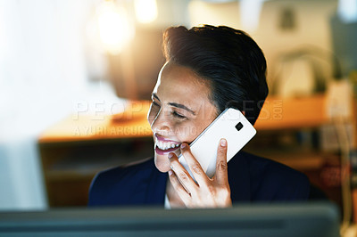 Buy stock photo Shot of a young businesswoman talking on a cellphone while working late in an office