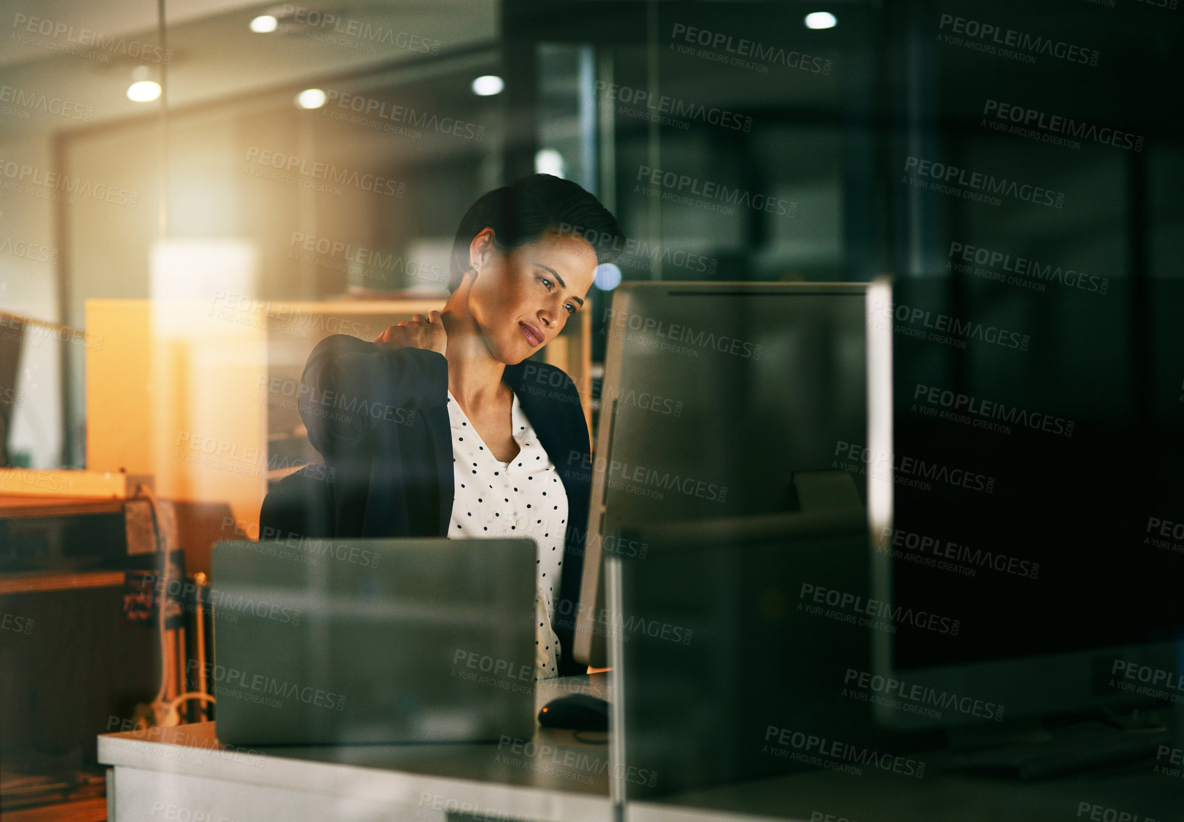 Buy stock photo Shot of a young businesswoman suffering with neck pain while working late in an office
