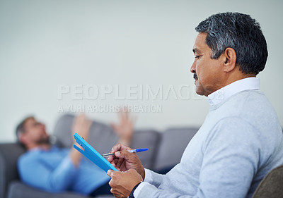 Buy stock photo Shot of a therapist taking notes while listening to a patient during a counseling session