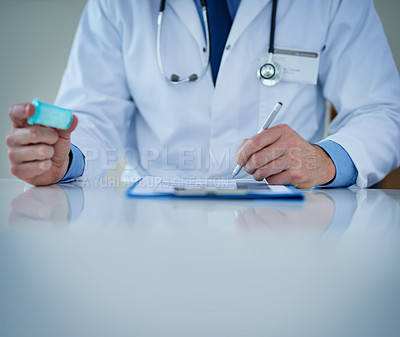 Buy stock photo Closeup shot of an unrecognizable doctor writing notes while holding a bottle of medication