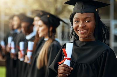Buy stock photo Portrait of a young woman holding her diploma while standing with her fellow students on graduation day