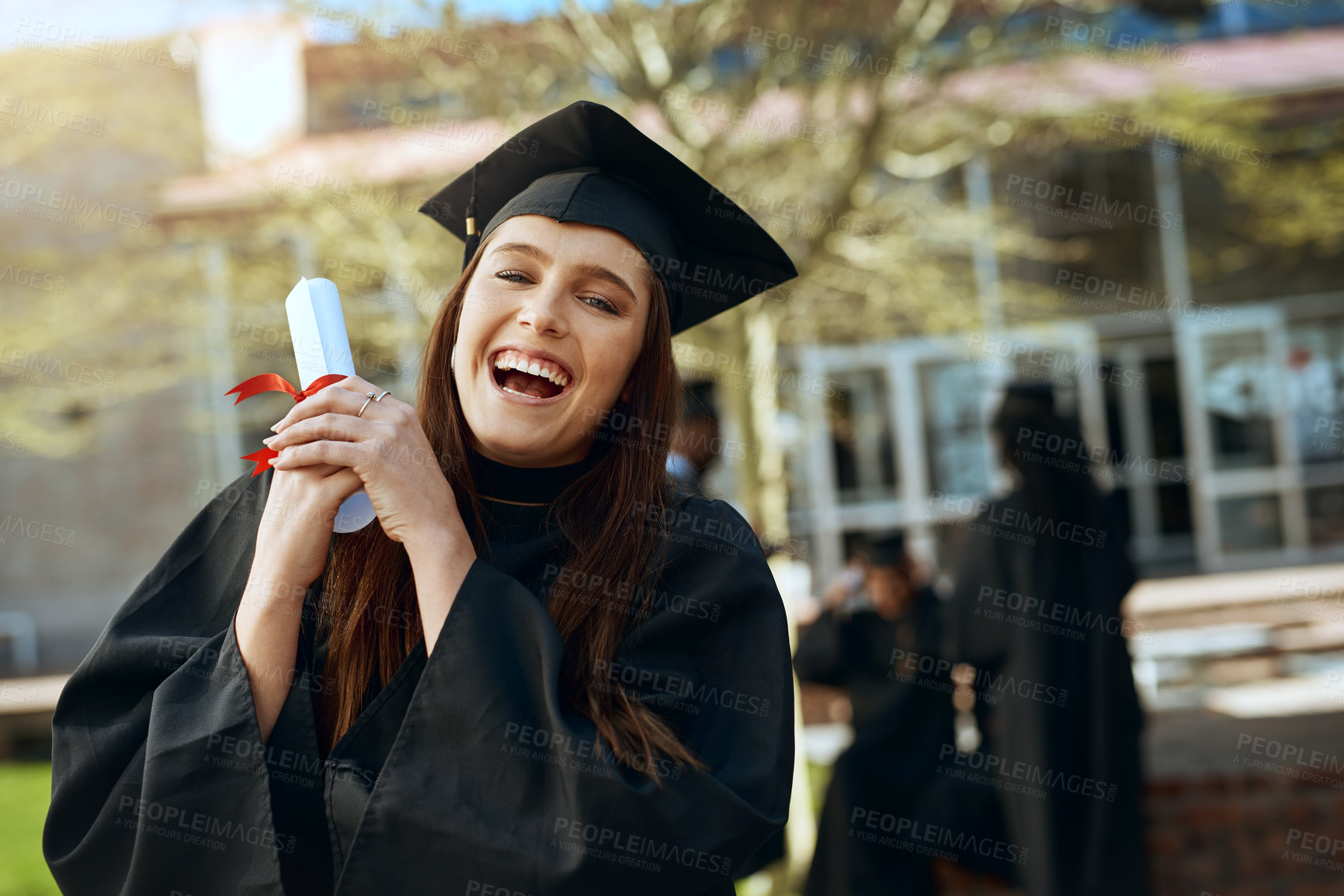 Buy stock photo Portrait of a happy young woman holding a diploma on graduation day