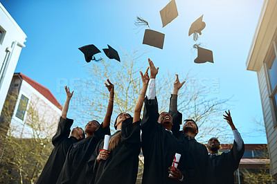 Buy stock photo Shot of a group of young students throwing their hats in the air on graduation day