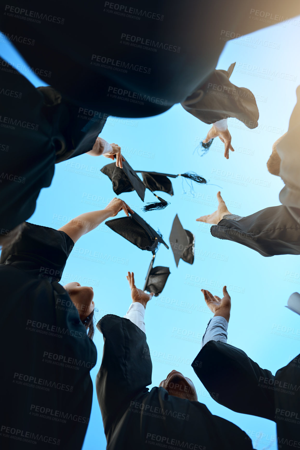 Buy stock photo Low angle shot of a group of young students throwing their hats in the air on graduation day