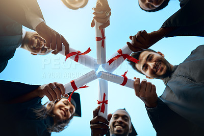 Buy stock photo Low angle shot of a group of students holding their diplomas together on graduation day