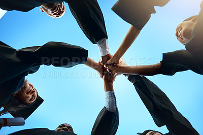 Buy stock photo Low angle shot of a group of young students joining their hands together on graduation day