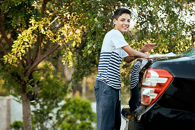 Buy stock photo Portrait of a cheerful young boy washing his parent's car outside during the day