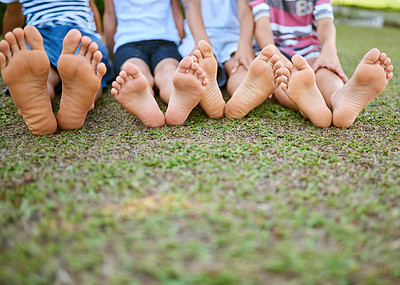 Buy stock photo Cropped shot of a group of kids sitting barefoot on grass