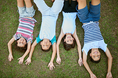 Buy stock photo High angle portrait of a group of happy siblings lying together on the grass