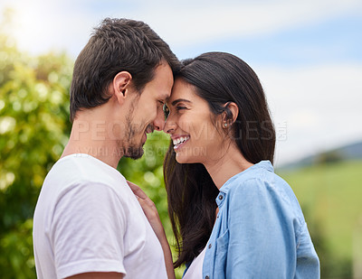 Buy stock photo Cropped shot of an affectionate young couple embracing while standing outdoors
