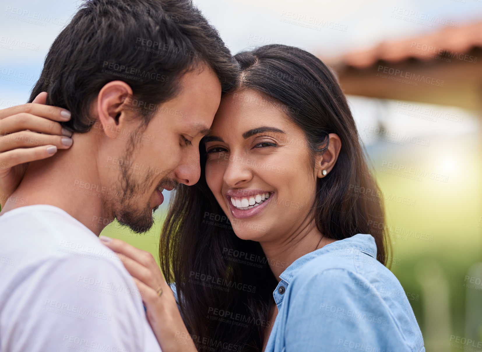 Buy stock photo Cropped shot of an affectionate young couple embracing while standing outdoors