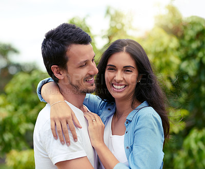 Buy stock photo Cropped shot of an affectionate young couple embracing while standing outdoors