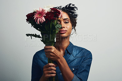 Buy stock photo Studio shot of an attractive young woman holding a bunch of flowers against a grey background