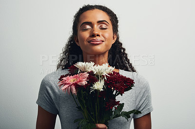 Buy stock photo Studio shot of an attractive young woman holding a bunch of flowers against a grey background