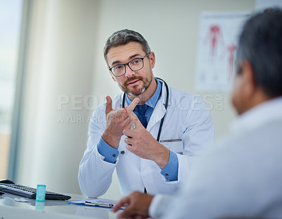 Buy stock photo Shot of a mature doctor having a consultation with a patient in his office