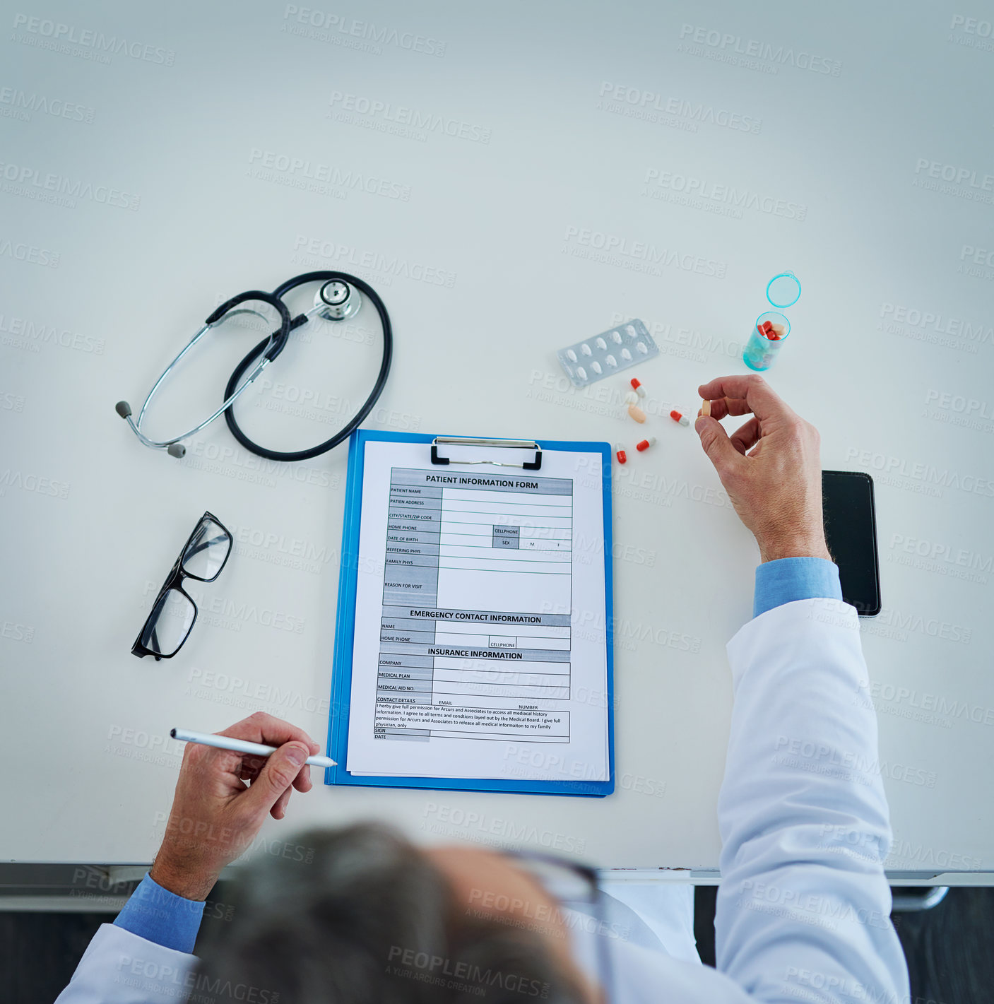 Buy stock photo High angle shot of an unrecognizable doctor busy with paperwork and medication in his office